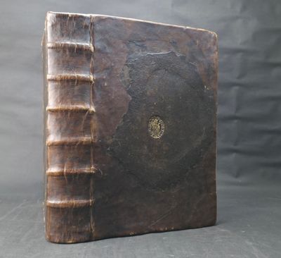 an old book with a brown cover sitting on top of a table