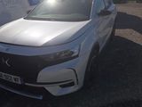 the front of a white car parked in a lot next to a trailer