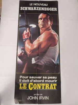 L'affiche du film « Le Contrat » est posée sur une table.