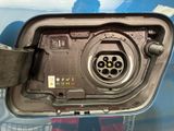 an image of a close up of a car ' s fuel tank with a person standing in the background