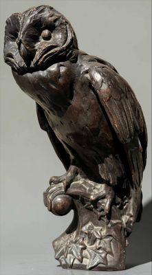 statue of an owl perched on a tree branch with a gray background