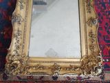 a gold framed mirror on a red rug on the floor