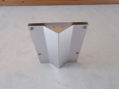 un petit objet blanc posé par terre, avec un mur en bois en arrière-plan