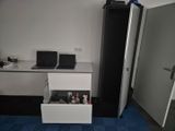 an image of a small room with a desk and a refrigerator