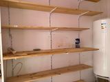 a water heater in the corner of a room next to a shelf