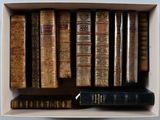 de nombreux livres anciens dans une boîte blanche posée sur une étagère