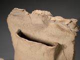 a clay vase with a hole in it on a table