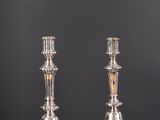 une paire de bougeoirs en argent posés sur une table, sur fond gris