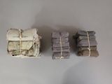three stacks of cloth wrapped in twine on a table
