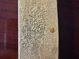 un lingot d'argent posé sur une table, sur laquelle se trouve une tache brune