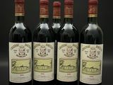 quatre bouteilles de vin rouge sont alignées sur une surface noire