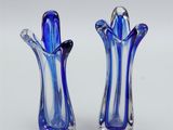 pair of blue glass vases sitting on top of a white surface