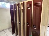 plusieurs casiers marron dans une pièce où se trouve une poubelle verte