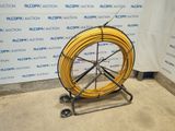 a yellow hose sitting on a cart in front of a wall