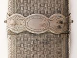 an antique silver cigarette case with a woven design on the front