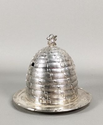 une assiette en argent surmontée d'un dôme, posée sur une surface grise
