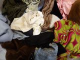 a pile of clothes on a bed with a teddy bear