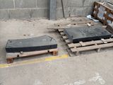 two pieces of black granite on pallets next to a brick wall