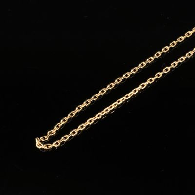 un gros plan d'un collier en or avec une chaîne sur fond noir