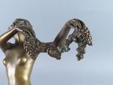 bronze statue of a woman holding a bunch of grapes in her hand