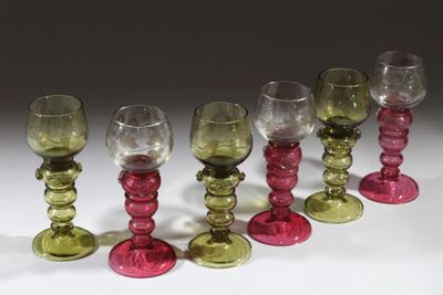 six verres à vin sont alignés sur une surface blanche