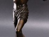 bronze statue of a man throwing a frisbee on a gray surface