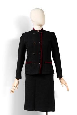 une photo d'un mannequin portant un tailleur-jupe noir orné de bordures rouges
