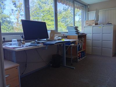 un ordinateur posé sur un bureau dans une pièce dotée d'une grande fenêtre