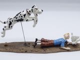 a figurine of a man laying on the ground with a dalmatian and a dog