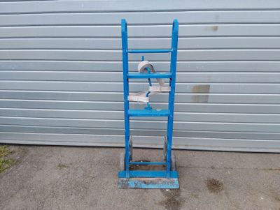 une échelle bleue sur laquelle est posée une cuvette de WC, devant la porte d'un garage