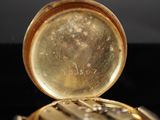 a close up of a gold pocket watch on a black surface
