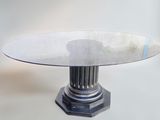 une table en verre avec un piètement en métal et un miroir posé dessus