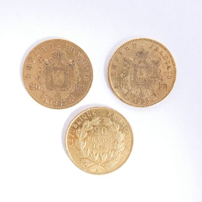 trois pièces d'or superposées sur une surface blanche