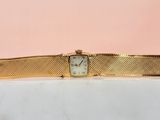 une montre-bracelet en or avec un cadran blanc sur fond rose