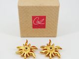 a pair of gold tone sunbursts in a cardboard box