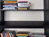 une bibliothèque noire sur laquelle sont posés de nombreux livres