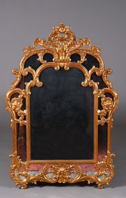 un cadre doré richement décoré surmonté d'un miroir