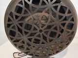 un vieux ventilateur en métal posé sur un pied, sur une surface blanche