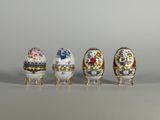 Quatre œufs de couleurs différentes sont alignés sur une table