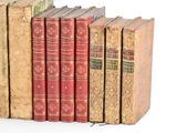 several old books are lined up in a row on a white surface