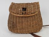 an old wicker purse with a leather strap on a white background
