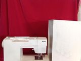 a white sewing machine sitting on a table next to a red cloth