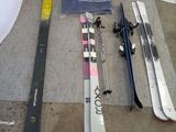 Plusieurs skis et snowboards sont alignés par terre