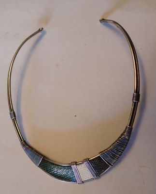collier argenté et bleu posé sur une table blanche, sur fond blanc
