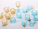 de nombreux verres et tasses de différentes couleurs posés sur une surface blanche