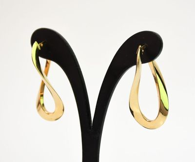 boucles d'oreilles dorées en forme de larme posées sur un support noir, sur fond blanc
