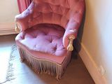 une chaise rose qui se trouve dans un coin d'une pièce