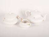 two white porcelain teapots and a saucer on a white surface