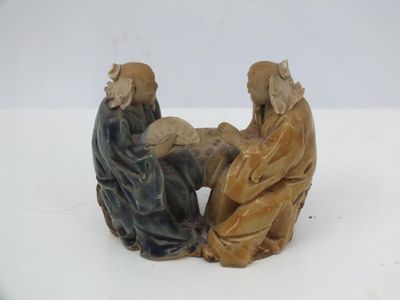 figurines représentant deux personnes assises sur une surface blanche, sur fond blanc