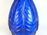 un vase en verre bleu orné d'un motif de feuilles